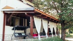 A covered outdoor seating area with a stone wall, a pergola, and a tree. - Apartment Peaceful Paradise (Bakar)
