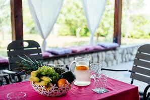 A table with a fruit basket, a pitcher, and glasses on a red tablecloth. - Apartment Peaceful Paradise (Bakar)