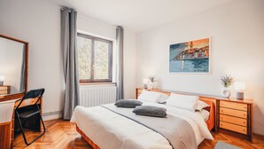 A modern bedroom with a large bed, a desk, and a window with curtains. - Apartment Peaceful Paradise (Bakar)