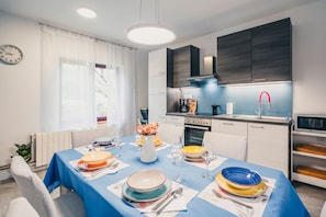 A modern kitchen with a dining area set for a meal. - Apartment Peaceful Paradise (Bakar)