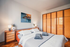 A bedroom with a bed, wooden nightstands, a large wardrobe, and a painting on the wall. - Apartment Peaceful Paradise (Bakar)