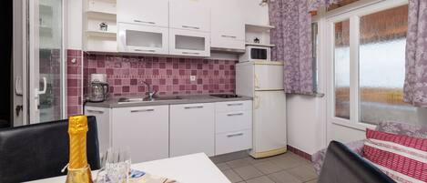 A compact kitchen with white cabinets, a microwave, and a refrigerator.