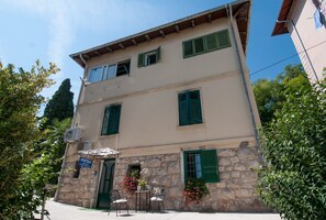 A two-story building with a stone facade, green shutters, and a sign indicating it is an apartment. - Apartments Lovran (Lovran)