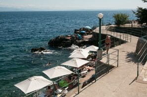 Une promenade en bord de mer, agrémentée de parasols et de coins salons offrant une vue sur la mer.