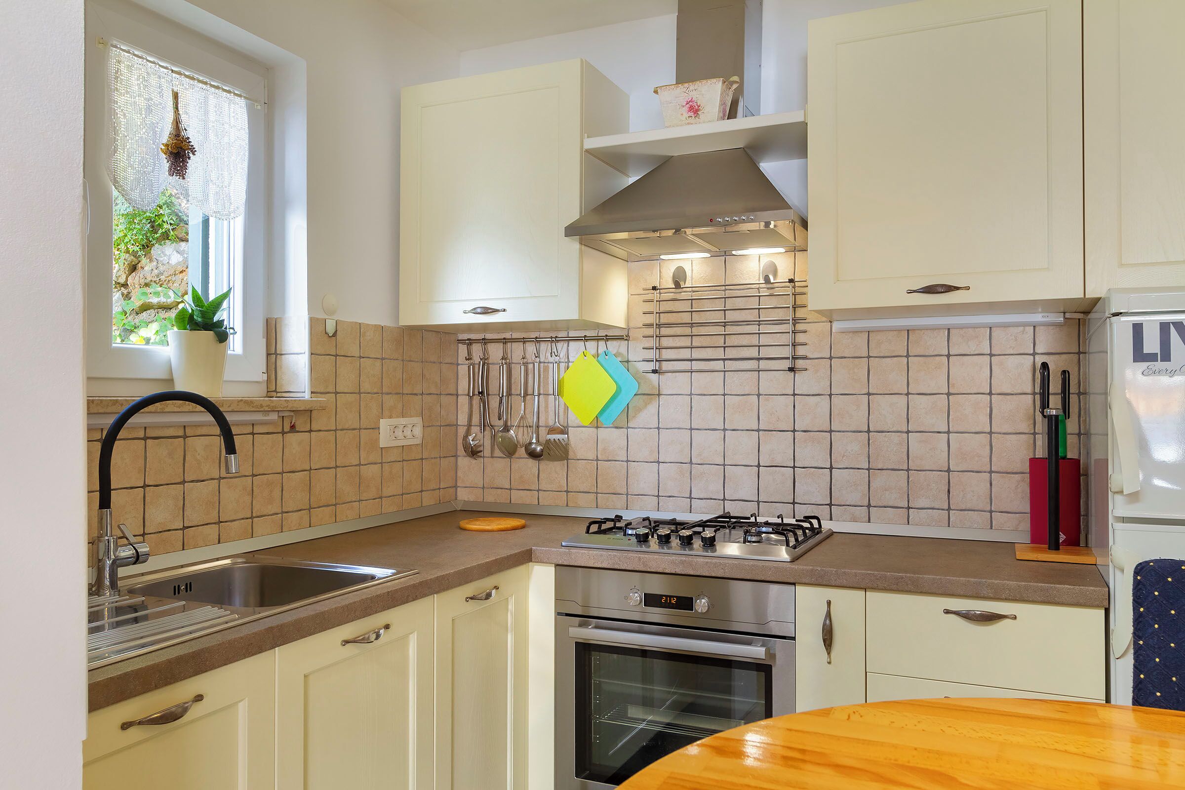 A kitchen with white cabinets, a gas stove, an oven, and a sink.
