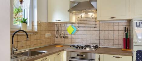 A kitchen with white cabinets, a gas stove, an oven, and a sink.