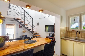 A modern kitchen with a wooden countertop, a built-in stove, a sink, and a staircase leading to an upper level. - Apartment Haus Kicer (Kraljevica)