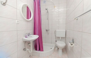 Ein Badezimmer mit Dusche, Toilette, Waschbecken und Spiegel.