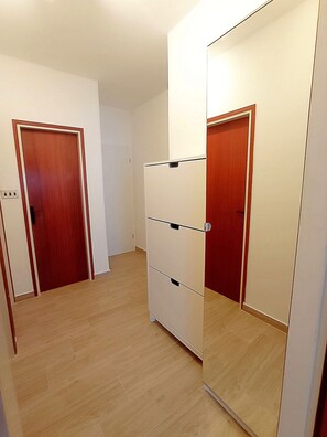 A hallway with a wooden floor, a white wall, and two doors. - Apartment Prcela 1 (Primosten)