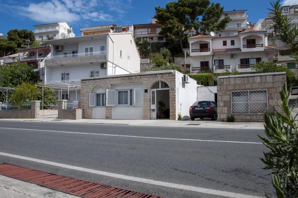 A street view with a row of residential buildings, a parked car, and a clear sky.