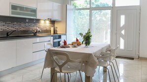 Una cucina moderna con mobili bianchi, un piano di lavoro nero e un'area pranzo con tavolo e sedie bianche.