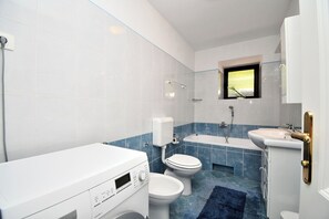 A modern bathroom with a toilet, sink, and bathtub. - House Iva i Ella (Opatija)
