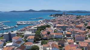 Un pueblo costero con un puerto deportivo, viviendas densas y un edificio destacado al fondo.