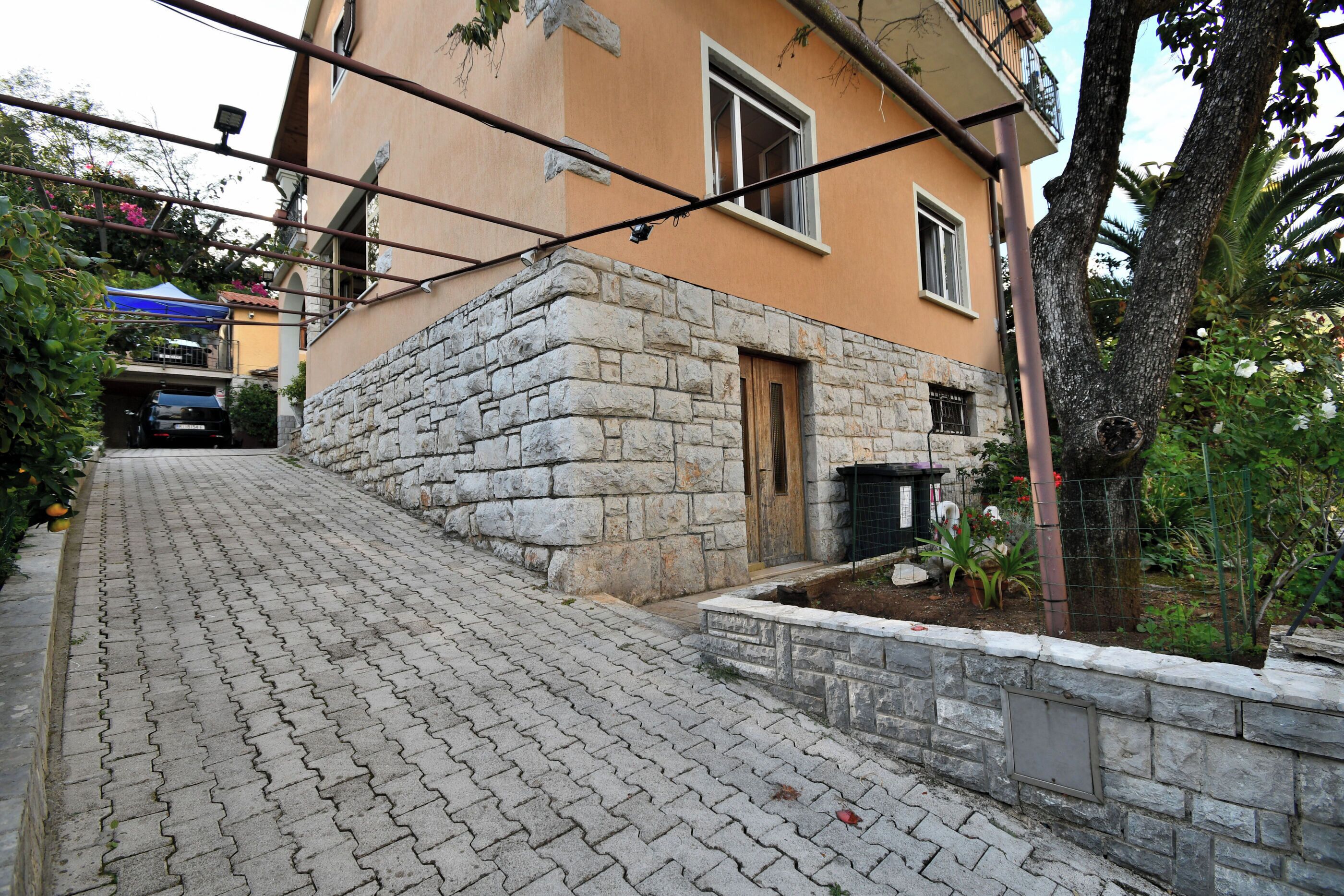 A paved pathway leading to a stone-walled building with a wooden door and windows.