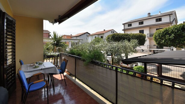 A balcony with a table and chairs, a view of neighboring houses, and a clear sky. - Apartment Elizabeta (Umag)