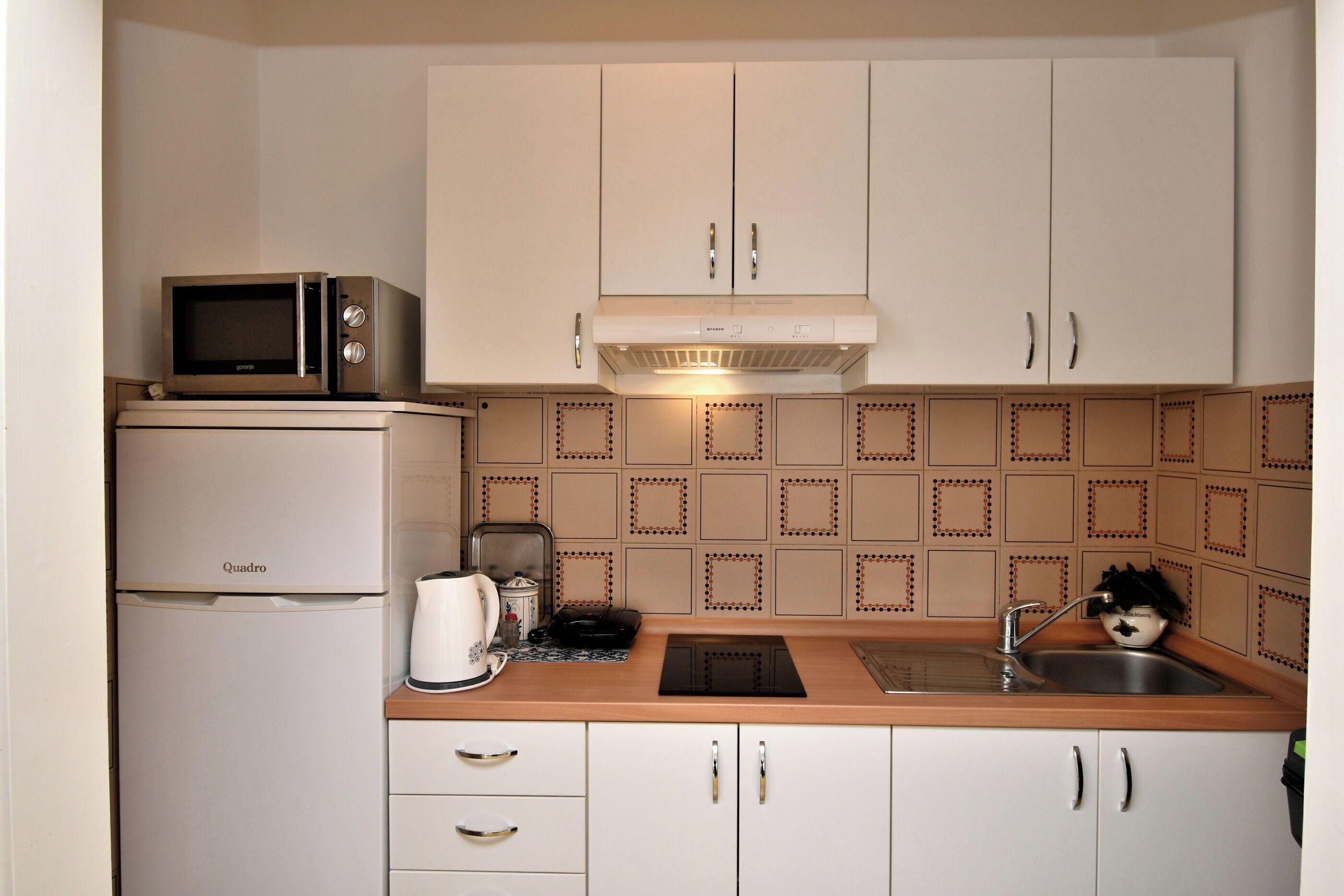 A compact kitchen with a microwave, refrigerator, and a sink.