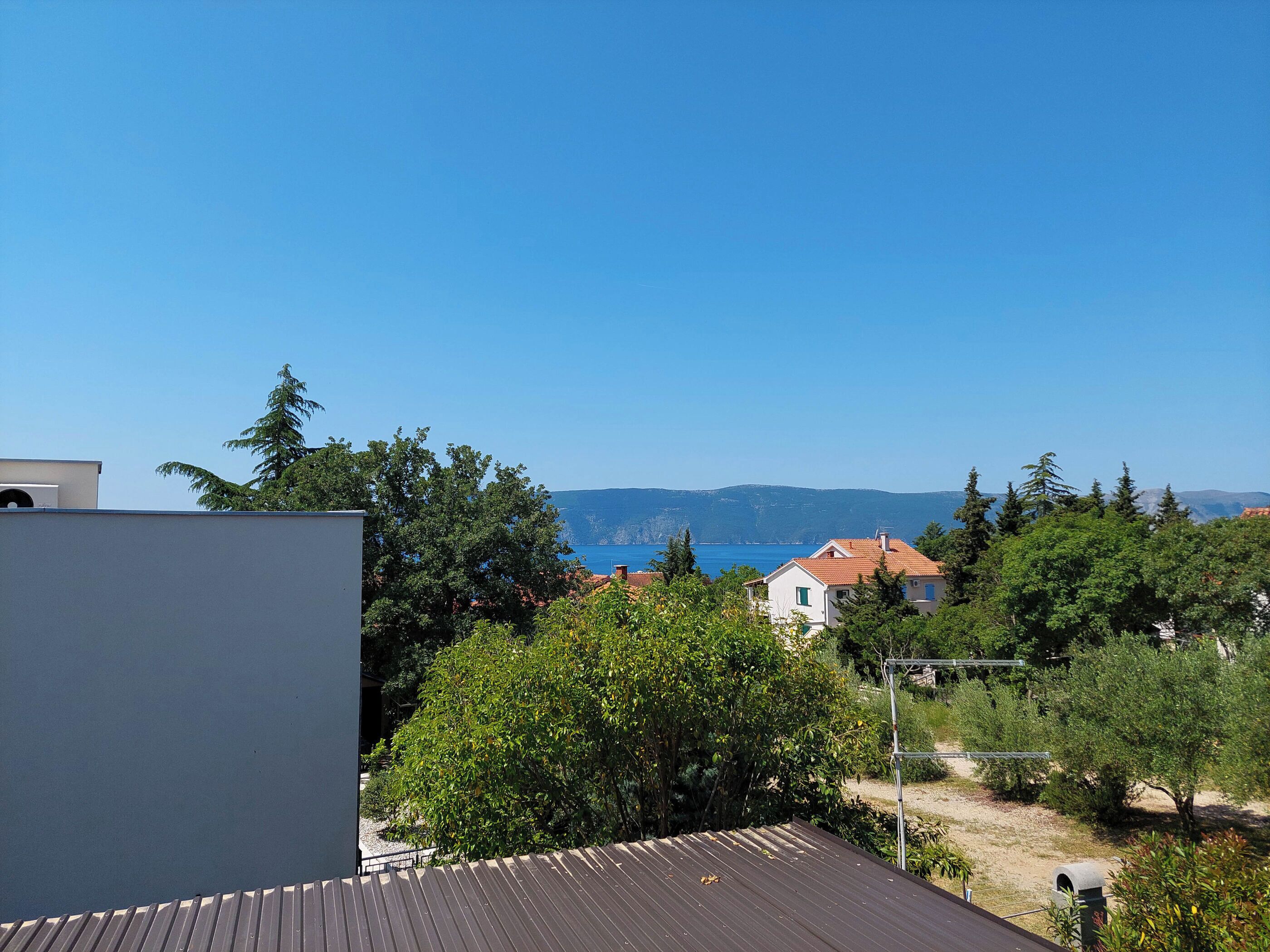 A residential area with a view of the sea and mountains in the background.