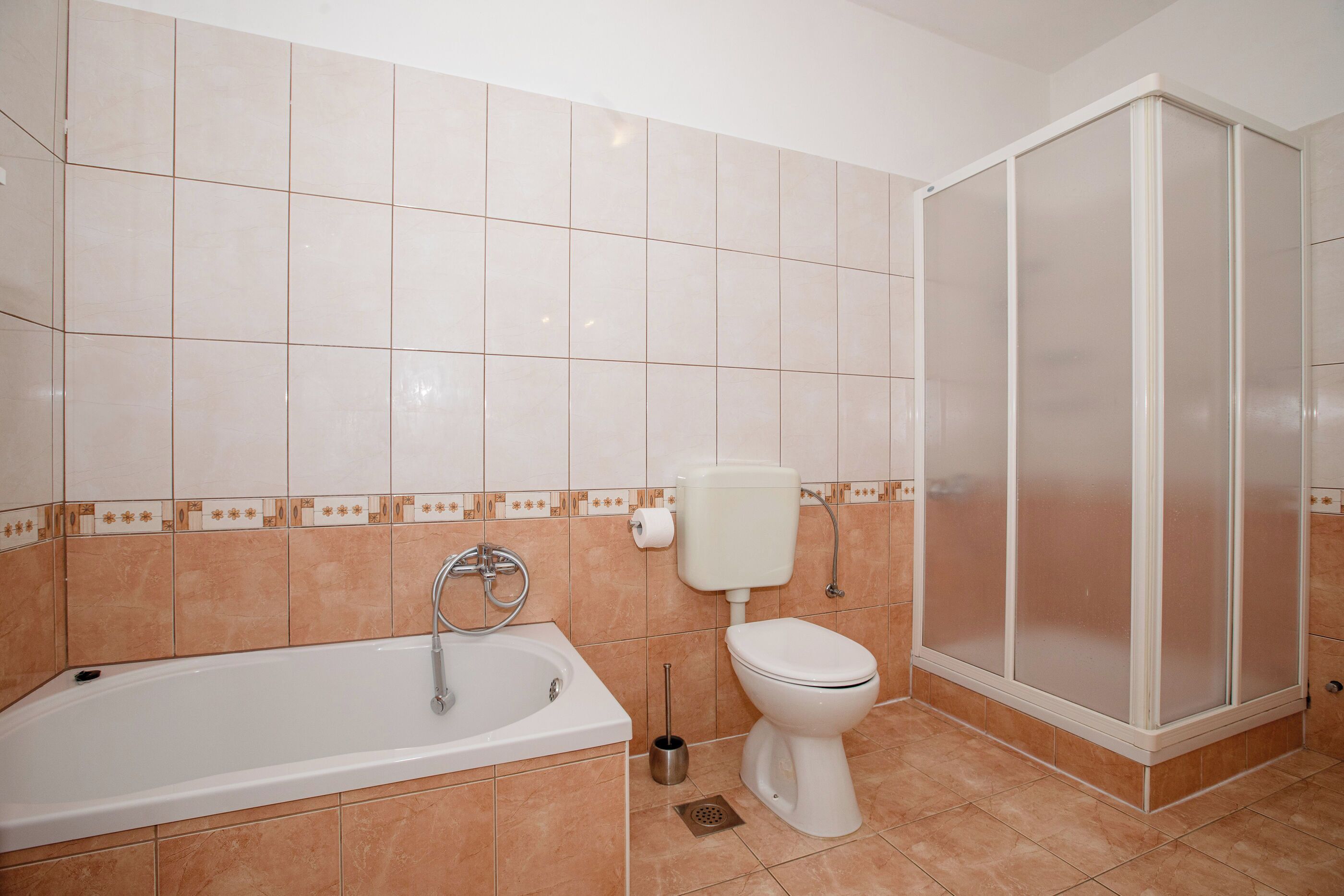 A bathroom with a bathtub, toilet, and shower enclosure.