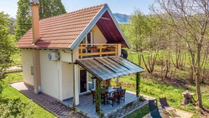 A house with a sloped roof, a covered porch, and a patio area with outdoor furniture. - House Jasenak (Gracac)