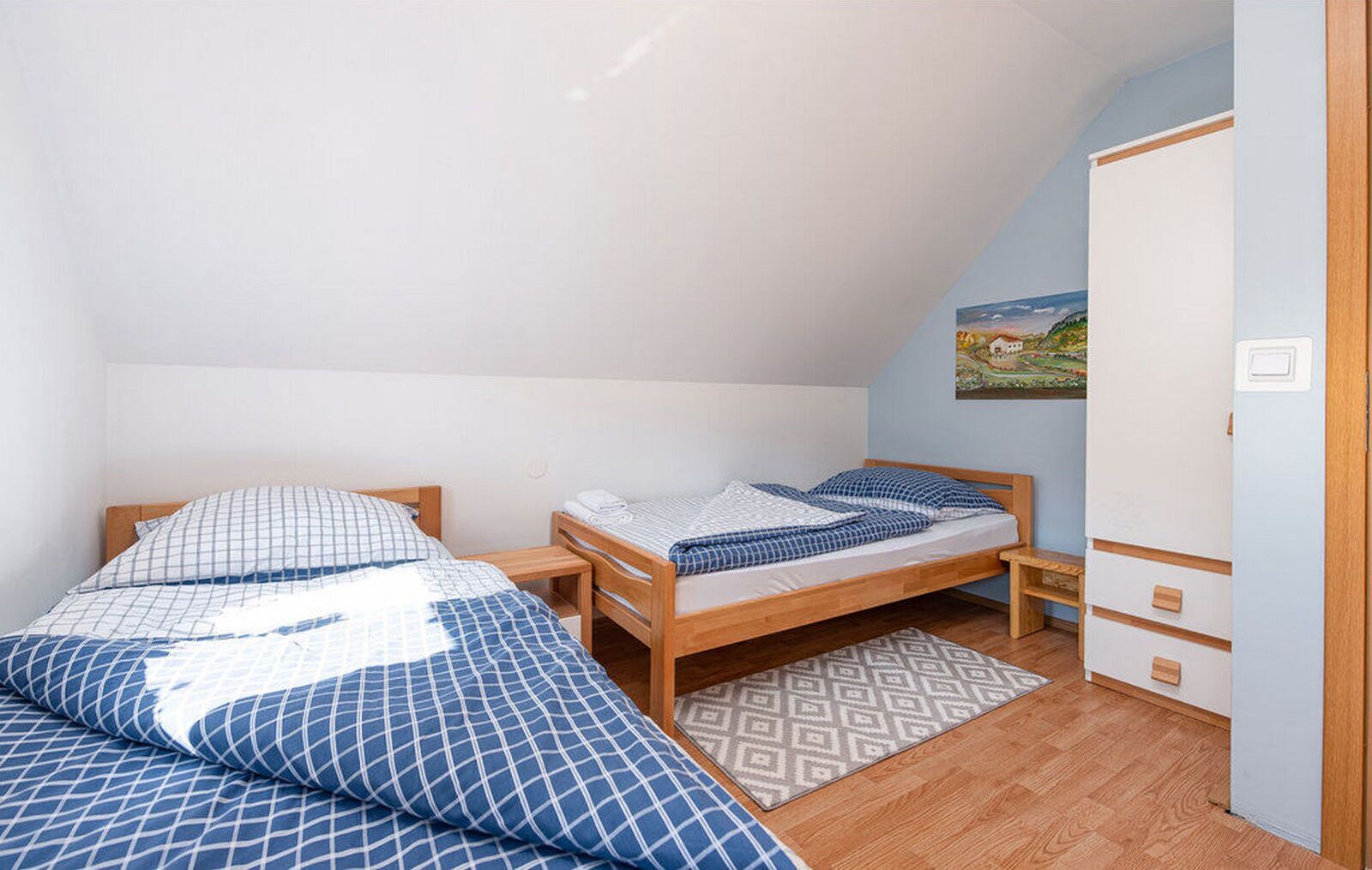 Quarto com duas camas, um guarda-roupa e um quadro na parede.