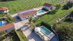 Une grande maison avec une piscine, un espace piscine séparé et un vignoble.