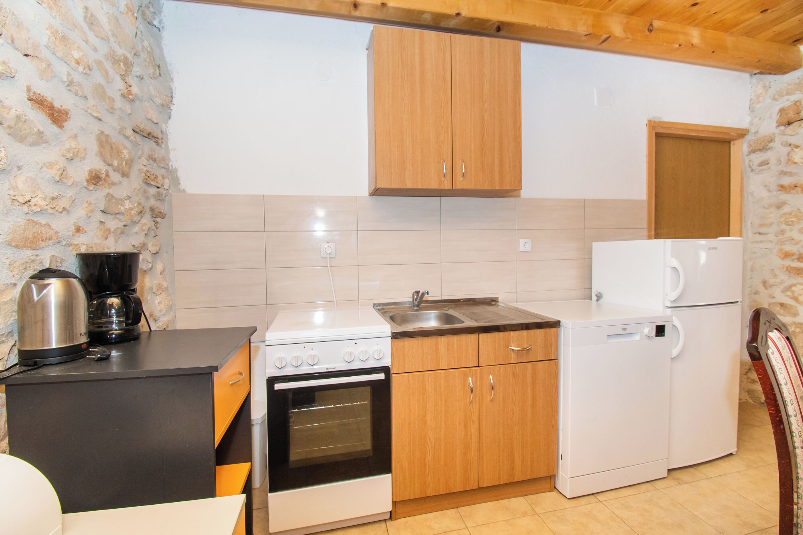 A compact kitchen with a stove, oven, sink, and a small refrigerator.