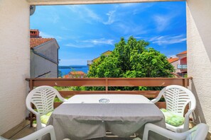 Un balcón con una mesa y dos sillas, con vista a un cuerpo de agua y edificios.