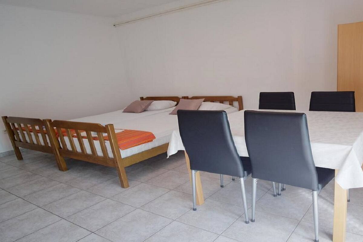 A bedroom with a bed, two chairs, a table, and a wardrobe.