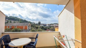 A balcony with a table and chairs, a drying rack, and a view of a residential area with houses and greenery. - Apartments Rucmarin (Pakostane)