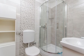 A modern bathroom with a glass-enclosed shower, a toilet, and a sink. - Apartment Niko (Sibenik)