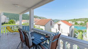 A balcony with a table and chairs, overlooking a coastal area with houses and a body of water. - Apartment Niko (Sibenik)
