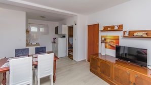 A compact living space with a dining area, kitchenette, and a TV on a wooden cabinet. - Apartment Niko (Sibenik)