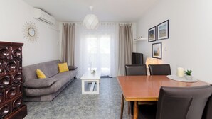 En moderne stue med en grå sofa, et træspisebord og et hvidt sofabord.
