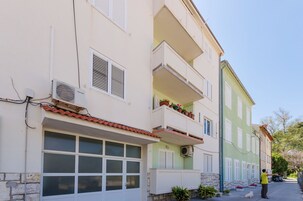 Un edificio de varios pisos con balcones, garaje y cielo despejado.