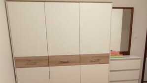 Ein Schlafzimmer mit einem Bett, Kissen, einem Kleiderschrank und einem Spiegel.