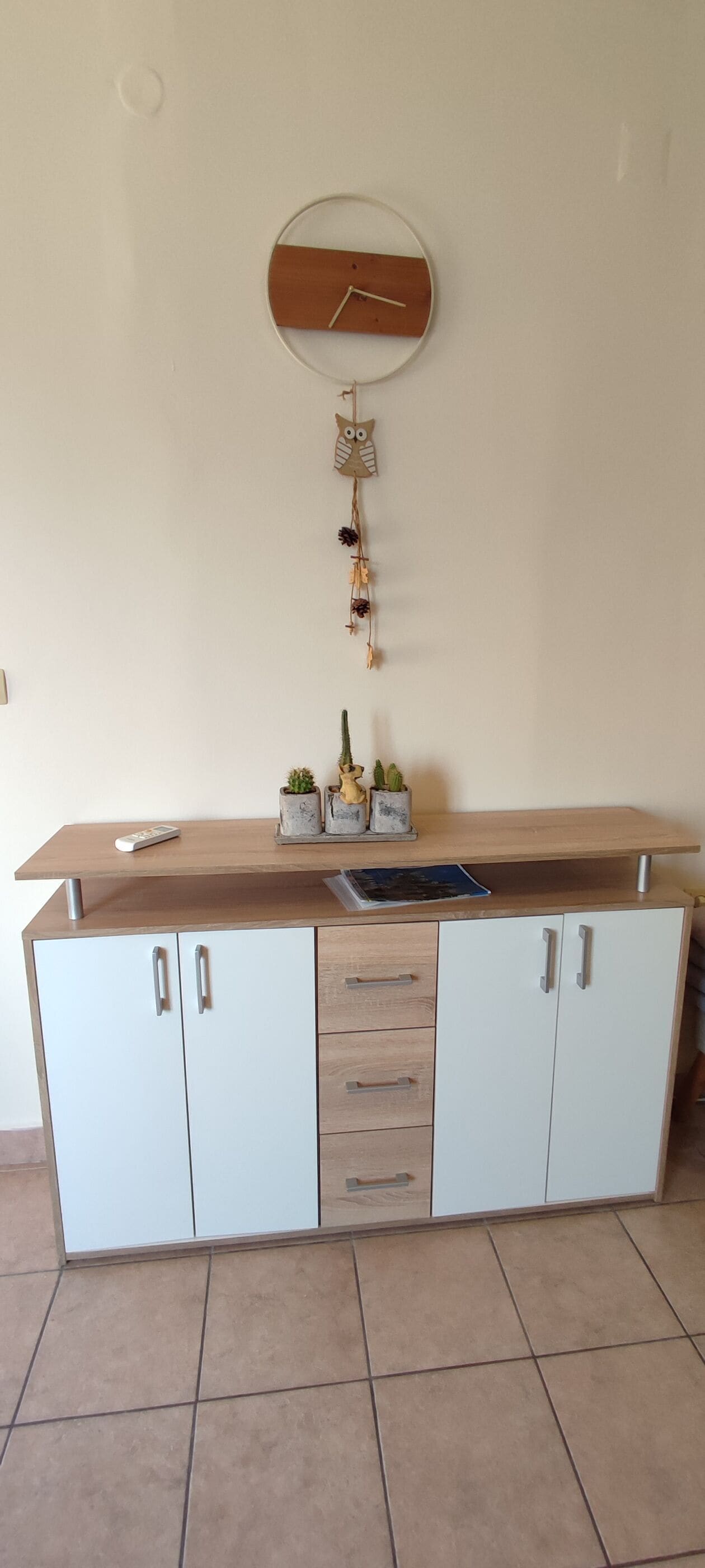 A kitchen with a wooden countertop, white cabinets, and a wall-mounted clock.