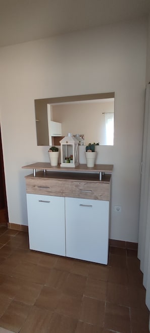 A kitchenette with a countertop, two cabinets, a mirror, and potted plants. - Apartment Meri (Lopar)