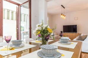 A dining area with a table set for two, featuring a vase with flowers and a bowl on the table. - Apartment Felix (Sukosan)