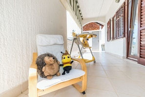 Un banco de madera con un cojín blanco, un erizo de peluche y un juguete de peluche con forma de abeja.