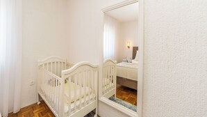 Un berceau blanc dans une pièce dont le sol est en bois, avec un miroir au mur et un rideau blanc.