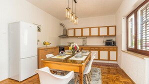 Une cuisine moderne avec une table à manger en bois, des chaises blanches et un four encastré.