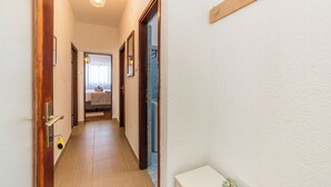 Un couloir avec des portes en bois, un mur blanc et une petite plante posée sur une table blanche.
