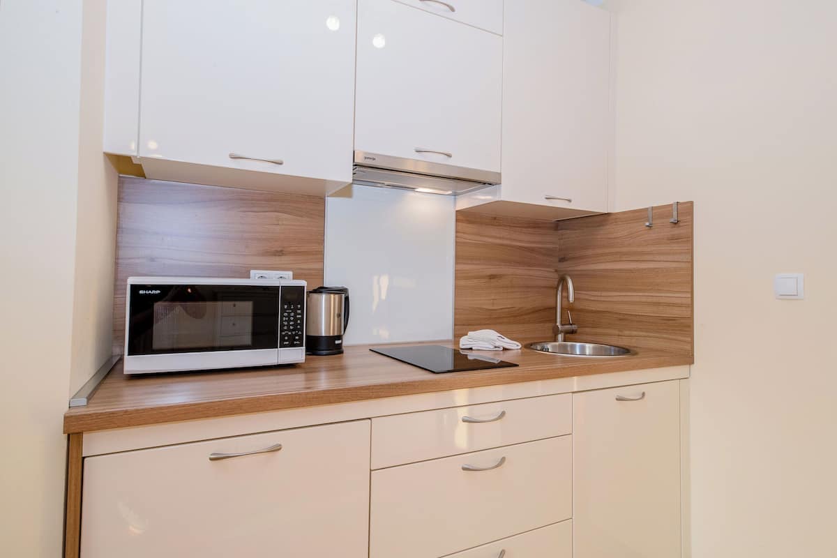 A modern kitchen with white cabinets, a stainless steel sink, a microwave, and a coffee maker.