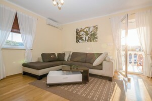 A living room with a sectional sofa, a coffee table, and a large window with curtains.