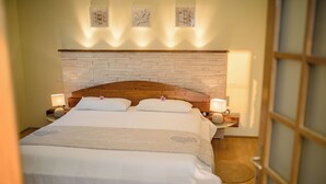 Una cama doble bien hecha, con cabecera de madera, dos lámparas de noche y un adorno decorativo en la pared.