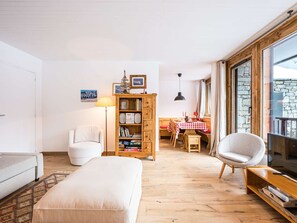 A cozy living room with a sofa, a wooden bookshelf, a dining table with a checkered tablecloth, and a television. - T3 Comfort Courchevel Moriond - 6 pers, Ski-in/out, Parking (Courchevel)