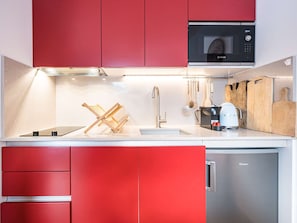 A modern kitchen with red cabinets, a Bosch microwave, a Canvy refrigerator, and various utensils. - T3 Comfort Courchevel Moriond - 6 pers, Ski-in/out, Parking (Courchevel)