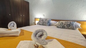 A hotel room with a neatly made bed, a wooden headboard, and a white textured wall. - Apartment Lada (Crikvenica)