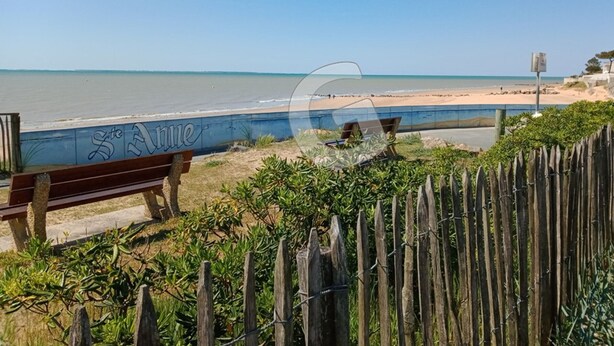 Une vue sur la plage avec une clôture en bois, un banc et un mur couvert de graffitis.