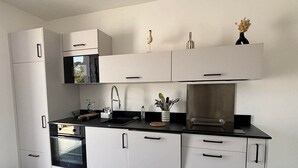 Une cuisine moderne avec des meubles blancs, un plan de travail noir et des appareils électroménagers en acier inoxydable.